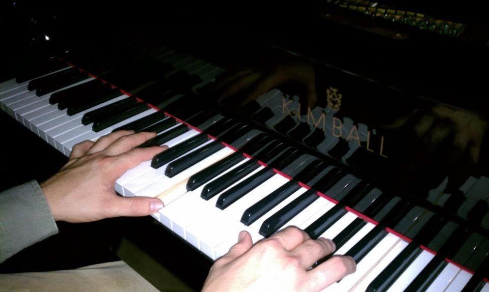 Hands playing the keys of a Kimball piano